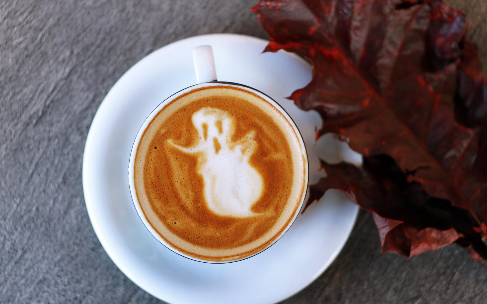 Ghost latte art coffee with autumn leaf decoration.