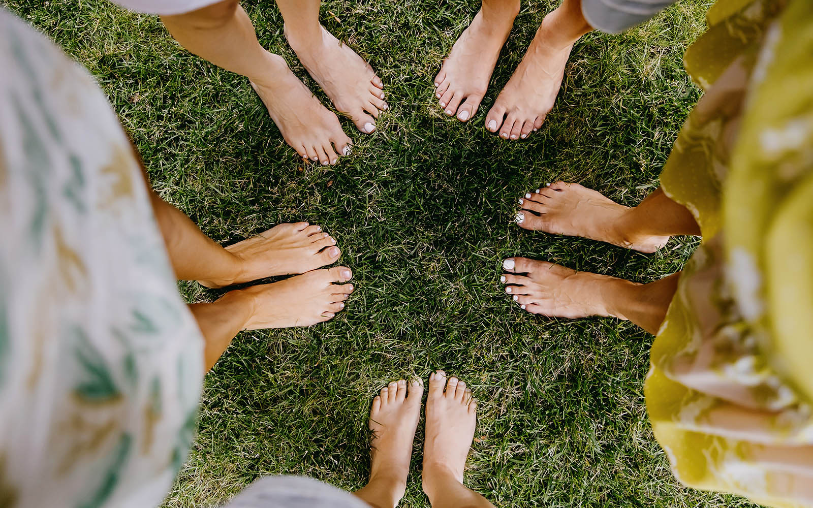 Bare feet forming circle on grass outdoors
