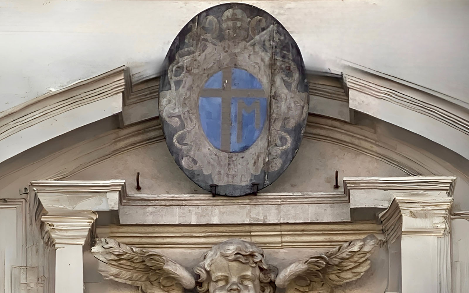 Historic emblem with angel sculpture on building facade.
