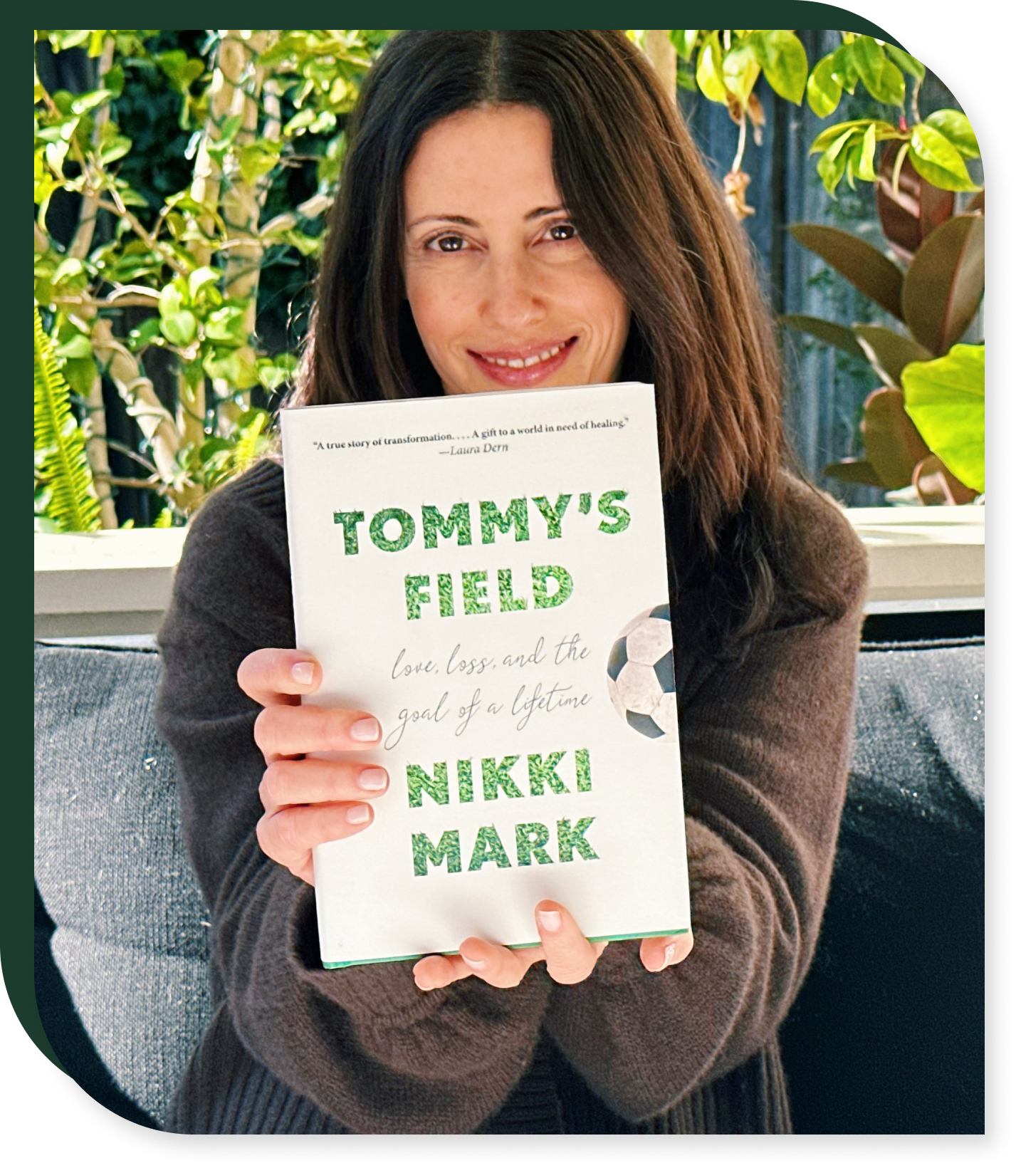 Woman holding a book titled "Tommy's Field
