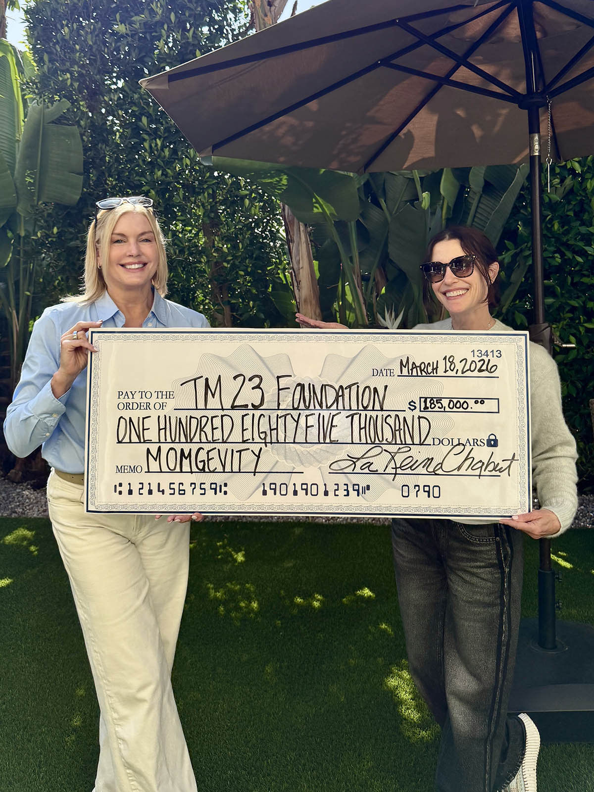 Two women holding a large donation check.
