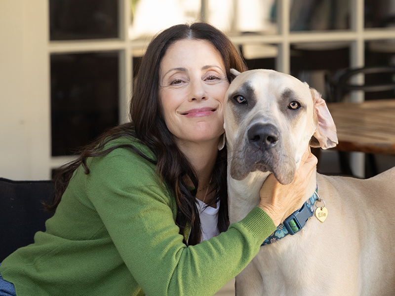 Woman in green sweater hugs large tan dog